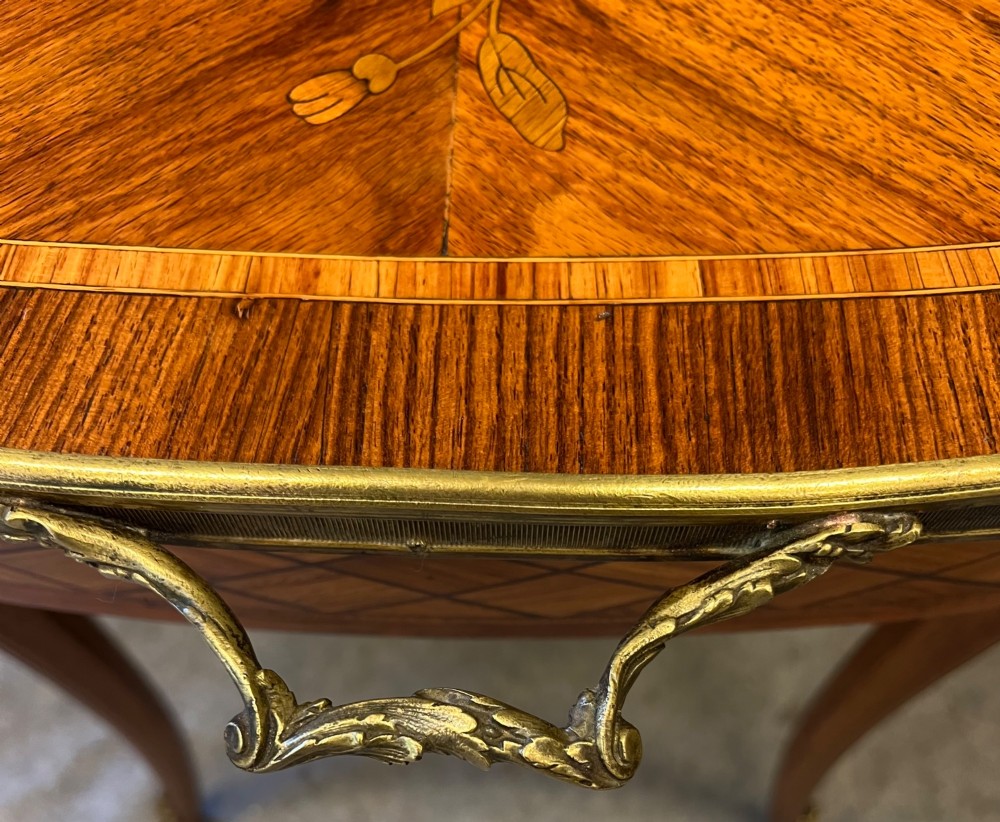 A French style low coffee table featuring floral marquetry inlay on top, diamond parquetry sides, cabriole legs, and brass corner mounts. View VII