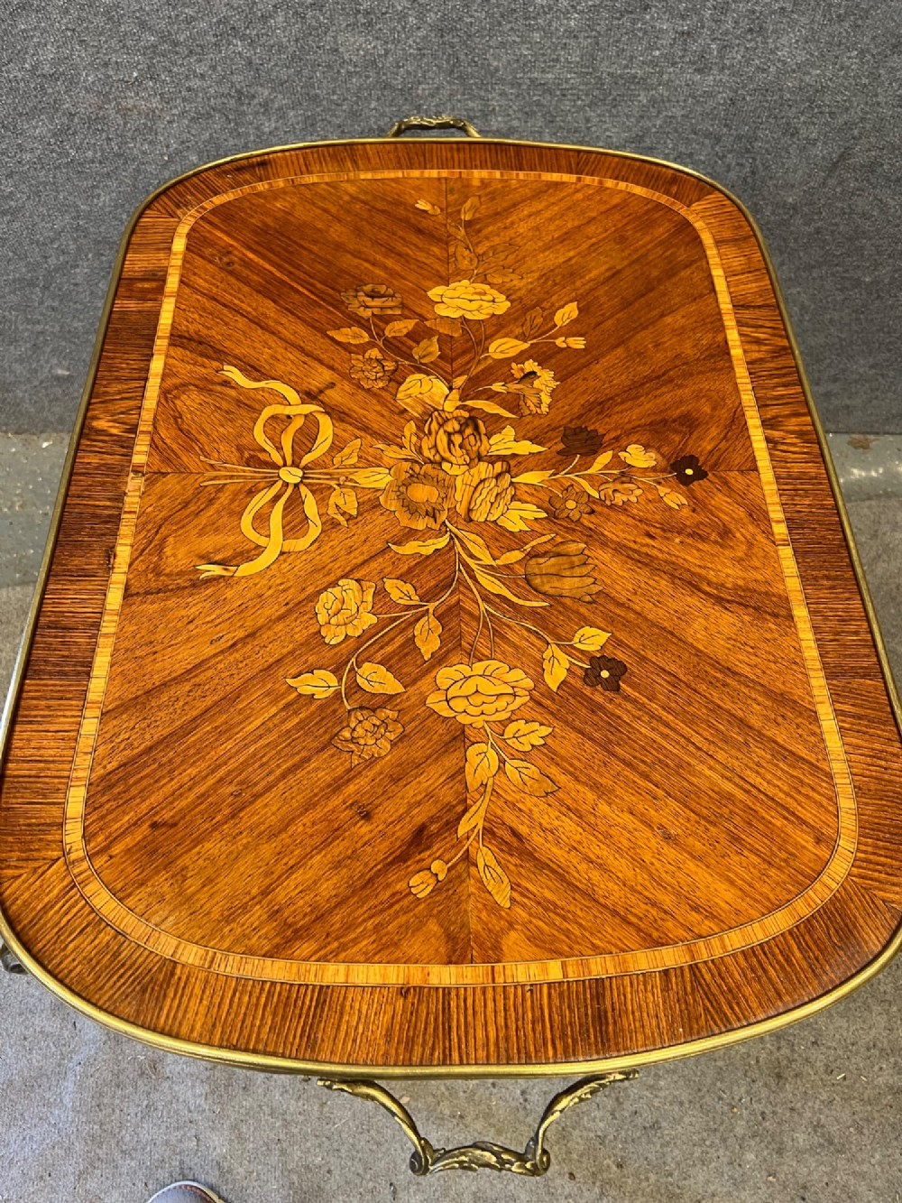 A French style low coffee table featuring floral marquetry inlay on top, diamond parquetry sides, cabriole legs, and brass corner mounts. View VIII