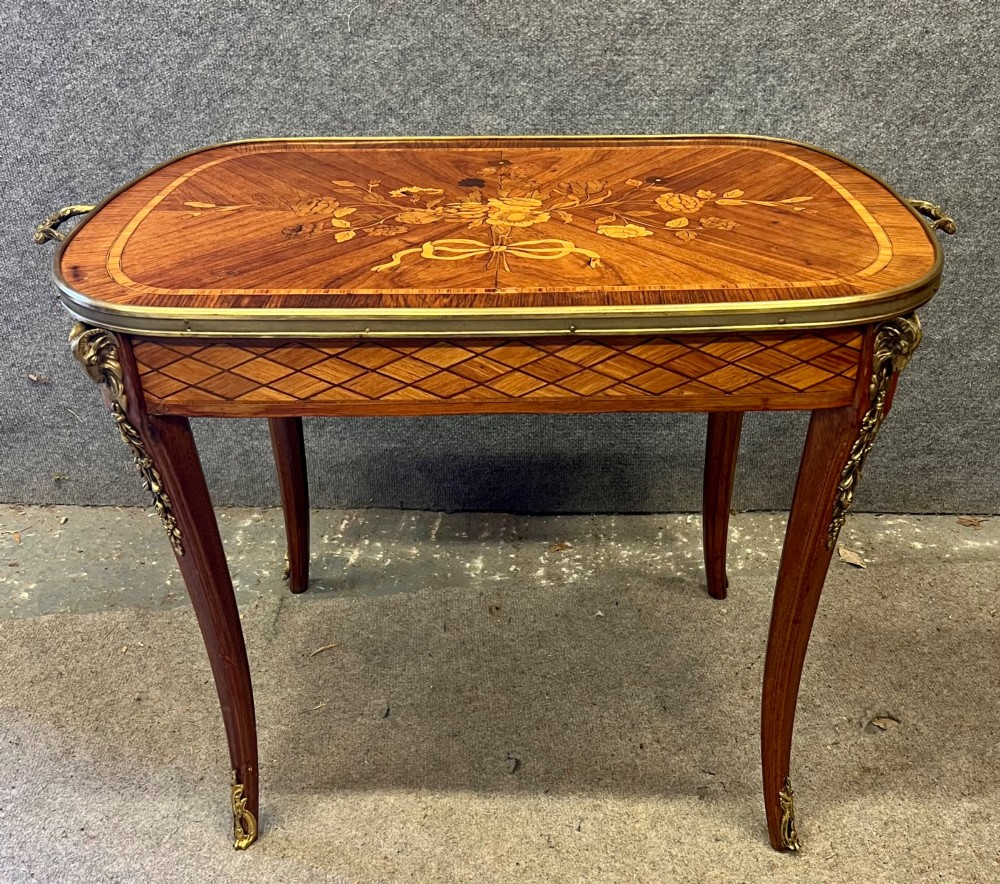 A French style low coffee table featuring floral marquetry inlay on top, diamond parquetry sides, cabriole legs, and brass corner mounts. View IX