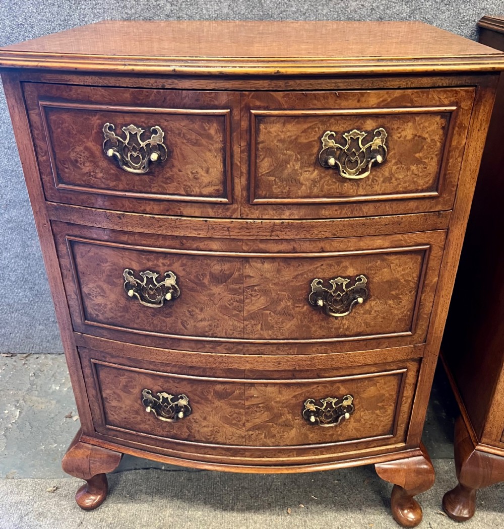 A matching pair of burr walnut bow-fronted bedside chests featuring four drawers with brass handles and cabriole legs. View V
