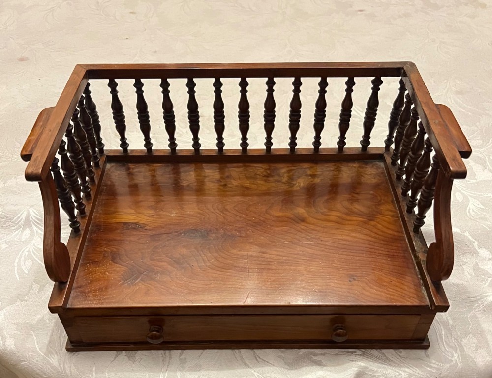 An antique yew wood desktop book trough featuring turned spindle gallery railings on three sides and a smooth timber base. View II