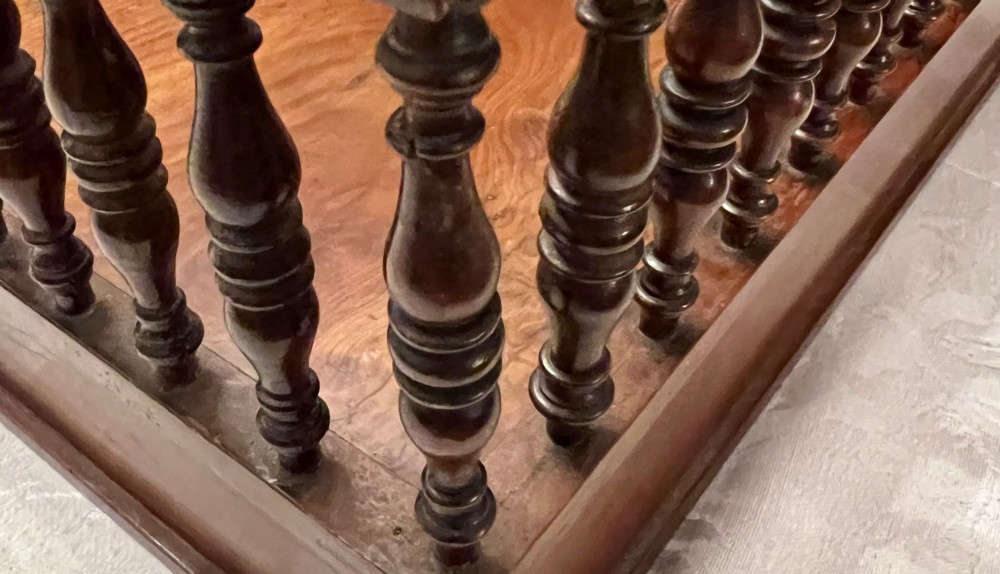 An antique yew wood desktop book trough featuring turned spindle gallery railings on three sides and a smooth timber base. View V