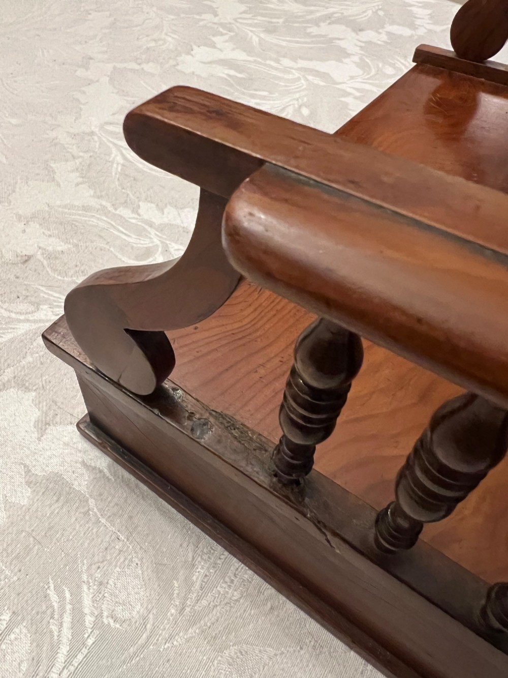An antique yew wood desktop book trough featuring turned spindle gallery railings on three sides and a smooth timber base. View VI