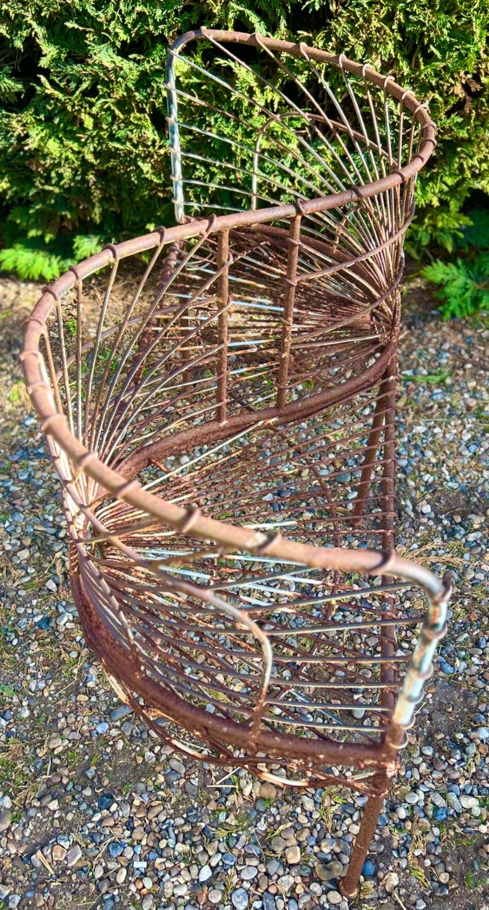 A weathered brown wrought iron S-shaped conversation seat featuring fan-patterned wire backrests and a looped apron base. View III