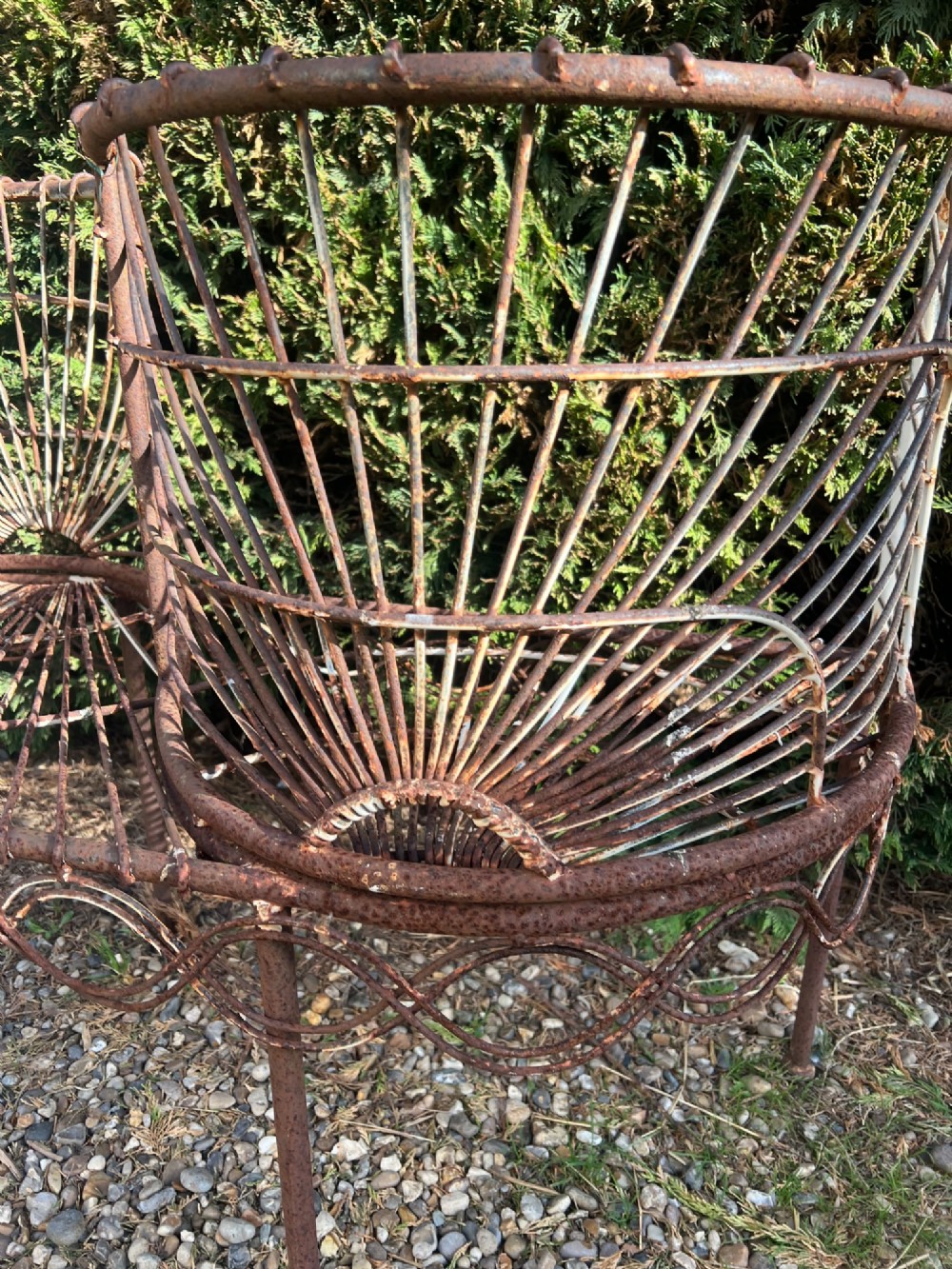 A weathered brown wrought iron S-shaped conversation seat featuring fan-patterned wire backrests and a looped apron base. View IV