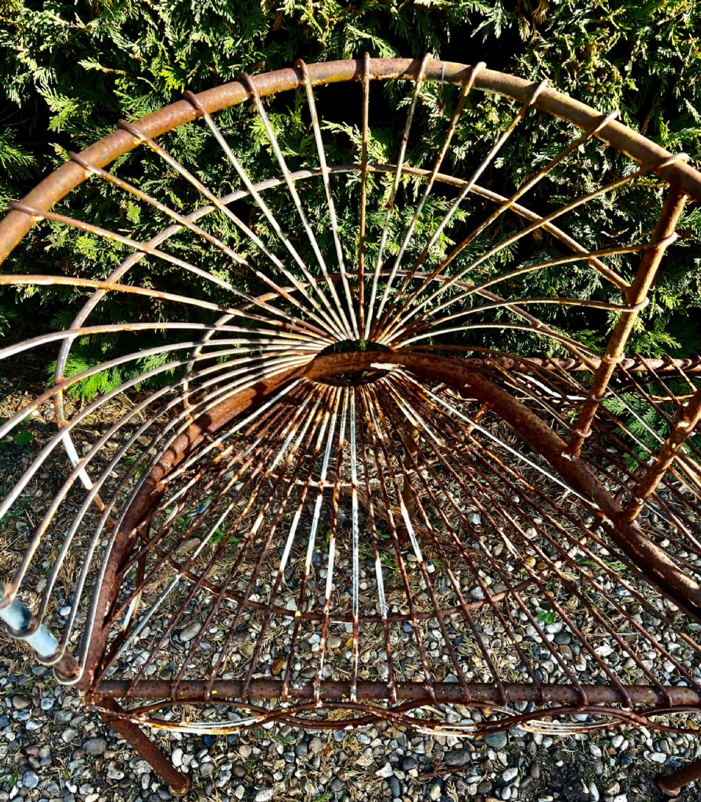 A weathered brown wrought iron S-shaped conversation seat featuring fan-patterned wire backrests and a looped apron base. View VIII