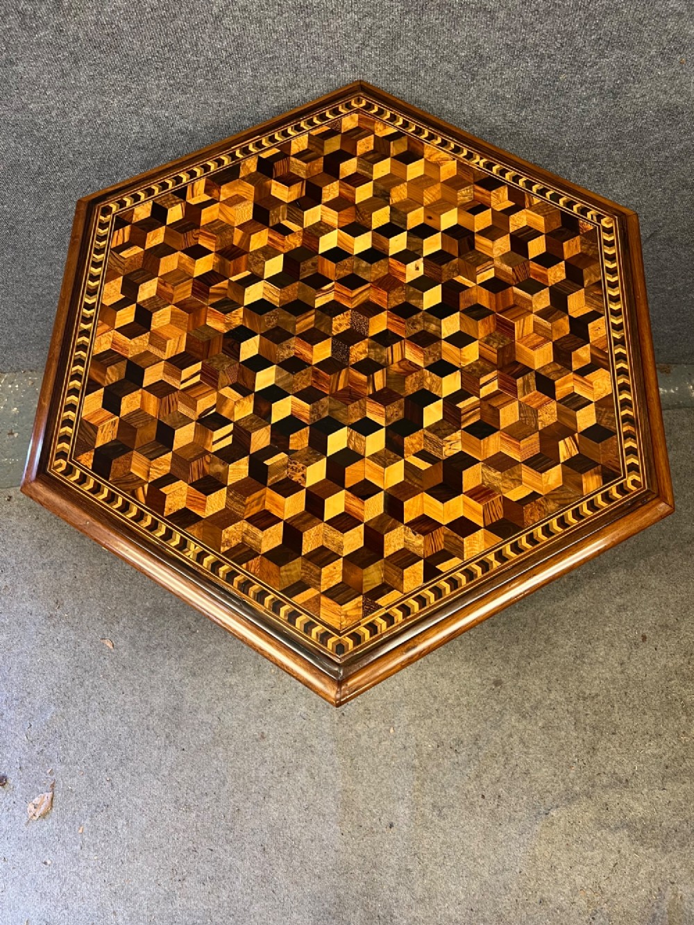 A 19th-century hexagonal specimen wood table featuring a geometric optical illusion parquetry top set on a carved central pedestal base. View II