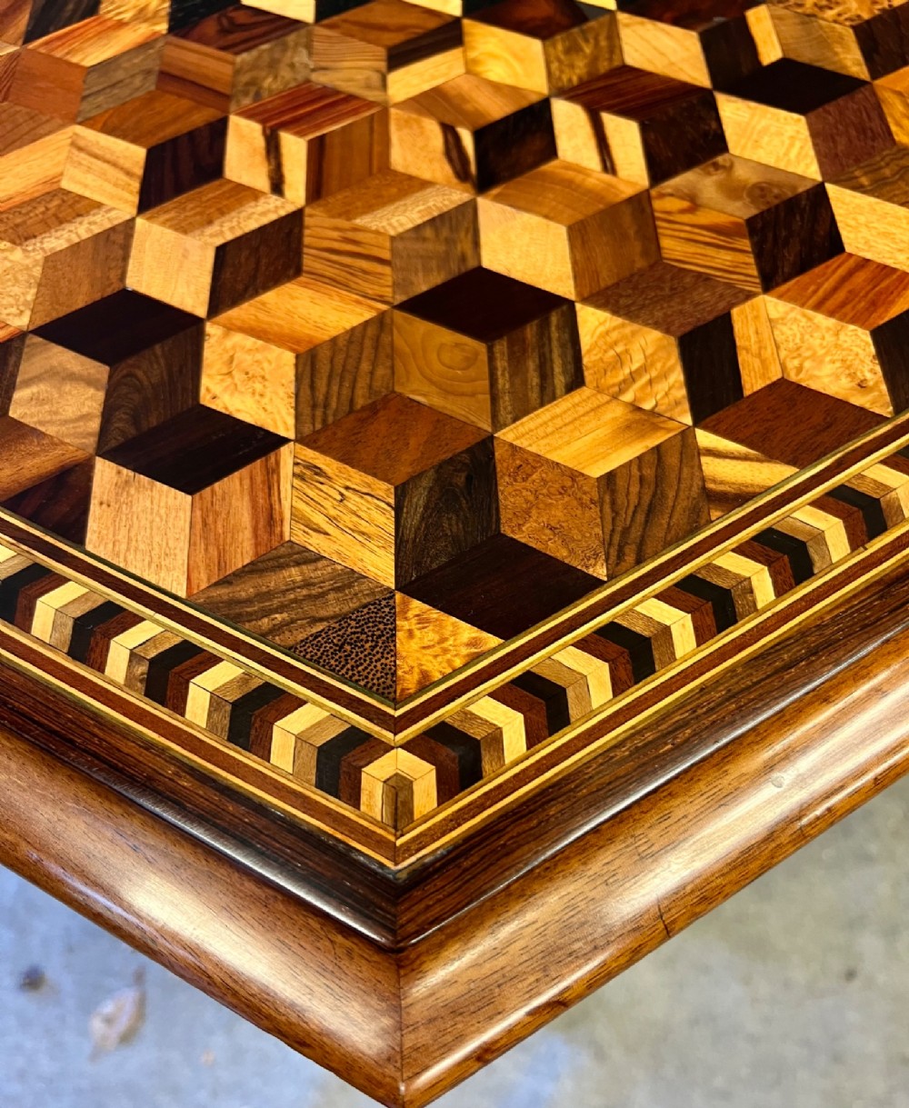 A 19th-century hexagonal specimen wood table featuring a geometric optical illusion parquetry top set on a carved central pedestal base. View X