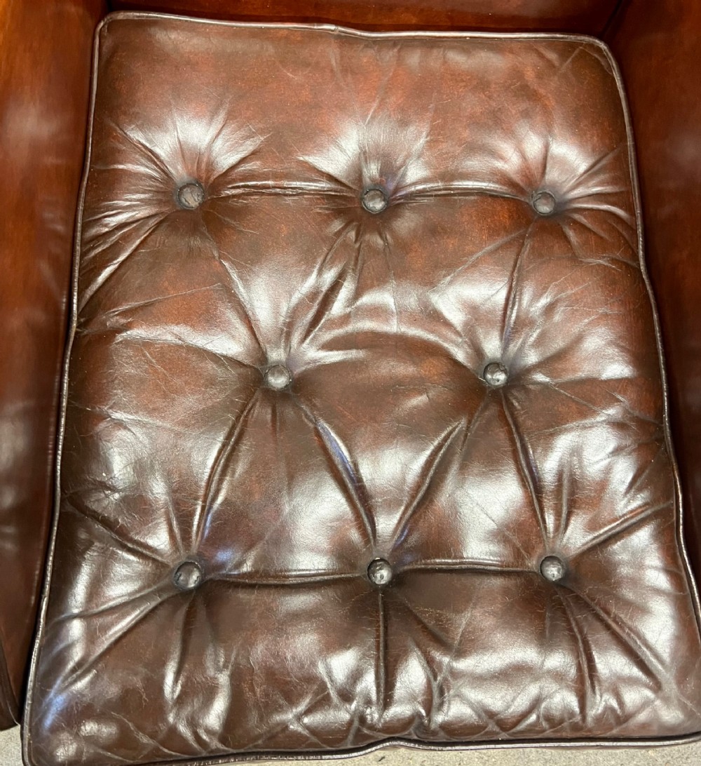A Georgian style warm brown leather wingback armchair featuring a button-tufted seat cushion, brass stud trim, and dark timber legs. View IV