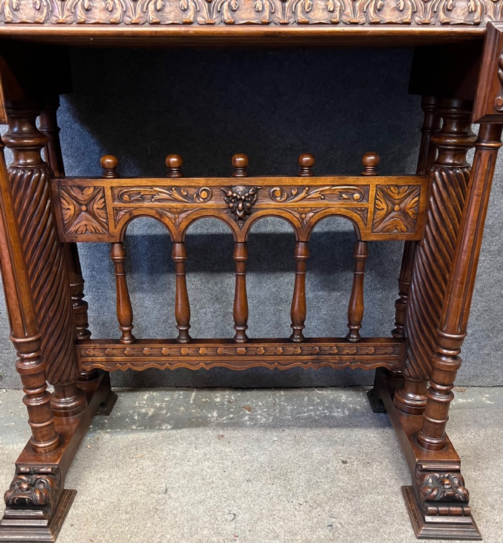 A carved Spanish vargueno cabinet in dark wood, featuring relief figures on the drop-front flap, decorative brass hardware, and a turned trestle stand. View XI
