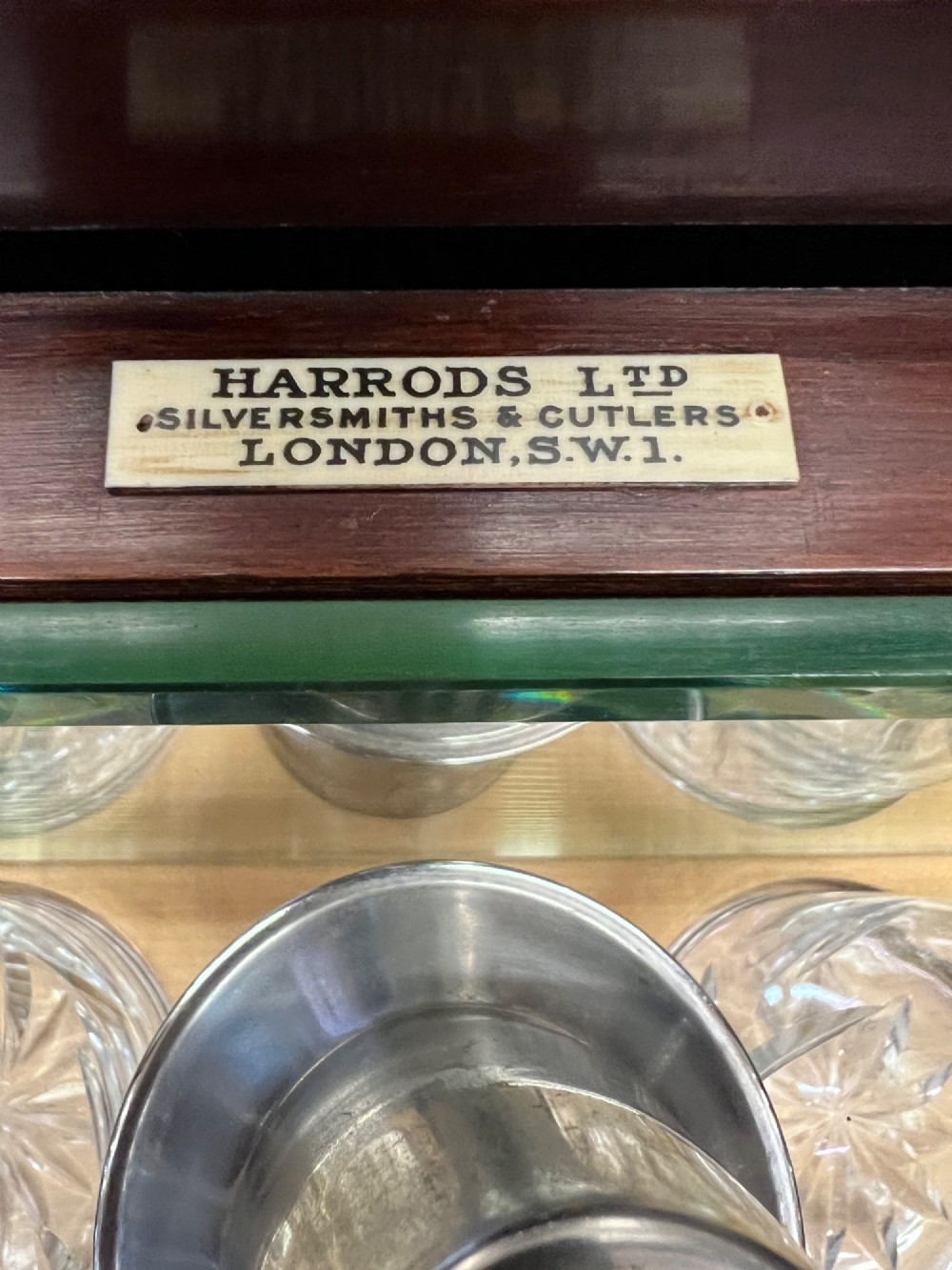 An open Art Deco walnut cocktail cabinet displaying a fitted mirrored interior with glassware, a silver-plated tray, and carved cabriole legs. View III