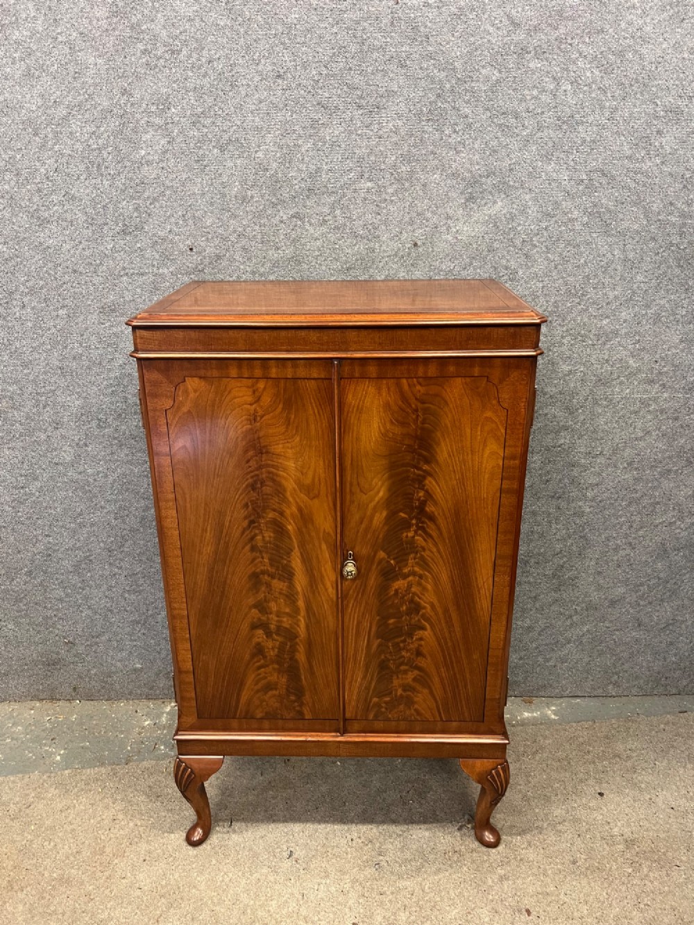 An open Art Deco walnut cocktail cabinet displaying a fitted mirrored interior with glassware, a silver-plated tray, and carved cabriole legs. View XI
