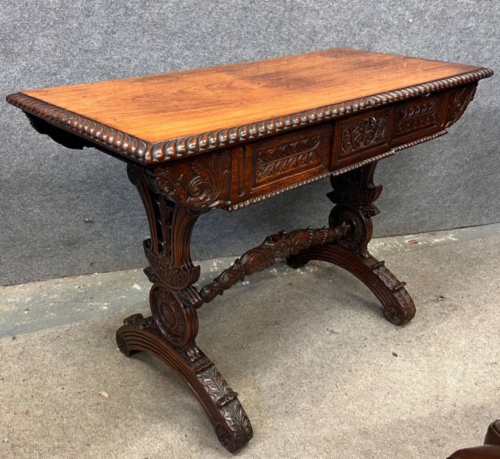 An Anglo-Indian carved hardwood centre table featuring a polished rectangular top, rope-twist carved borders, relief-carved frieze drawers, and detailed trestle legs. View III