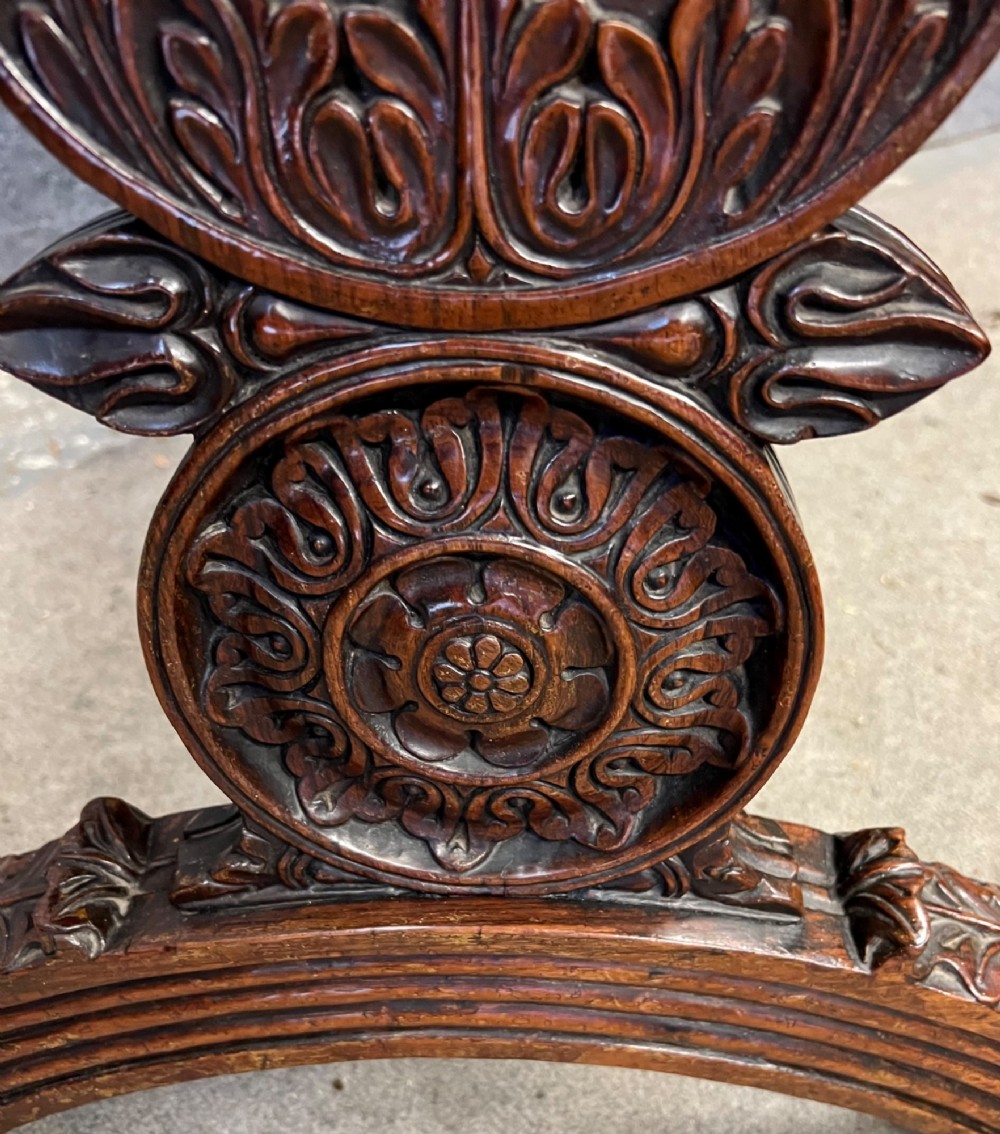 An Anglo-Indian carved hardwood centre table featuring a polished rectangular top, rope-twist carved borders, relief-carved frieze drawers, and detailed trestle legs. View V