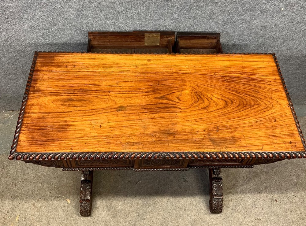 An Anglo-Indian carved hardwood centre table featuring a polished rectangular top, rope-twist carved borders, relief-carved frieze drawers, and detailed trestle legs. View VII