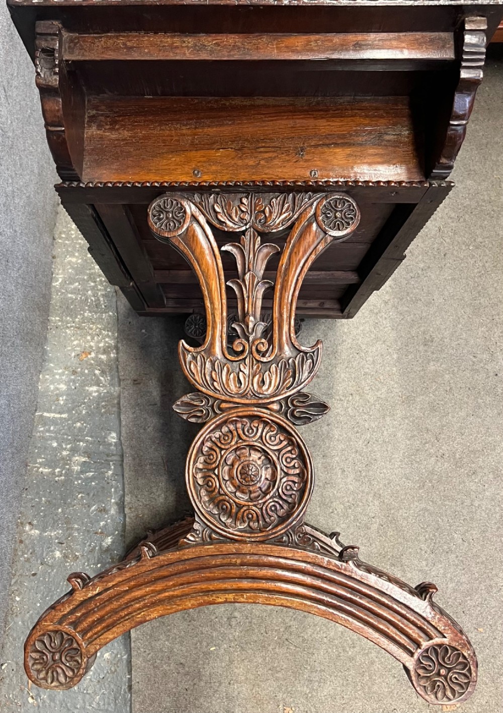 An Anglo-Indian carved hardwood centre table featuring a polished rectangular top, rope-twist carved borders, relief-carved frieze drawers, and detailed trestle legs. View XI