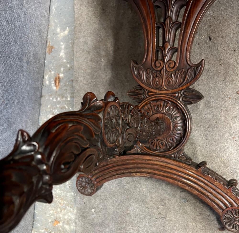 An Anglo-Indian carved hardwood centre table featuring a polished rectangular top, rope-twist carved borders, relief-carved frieze drawers, and detailed trestle legs. View XIII