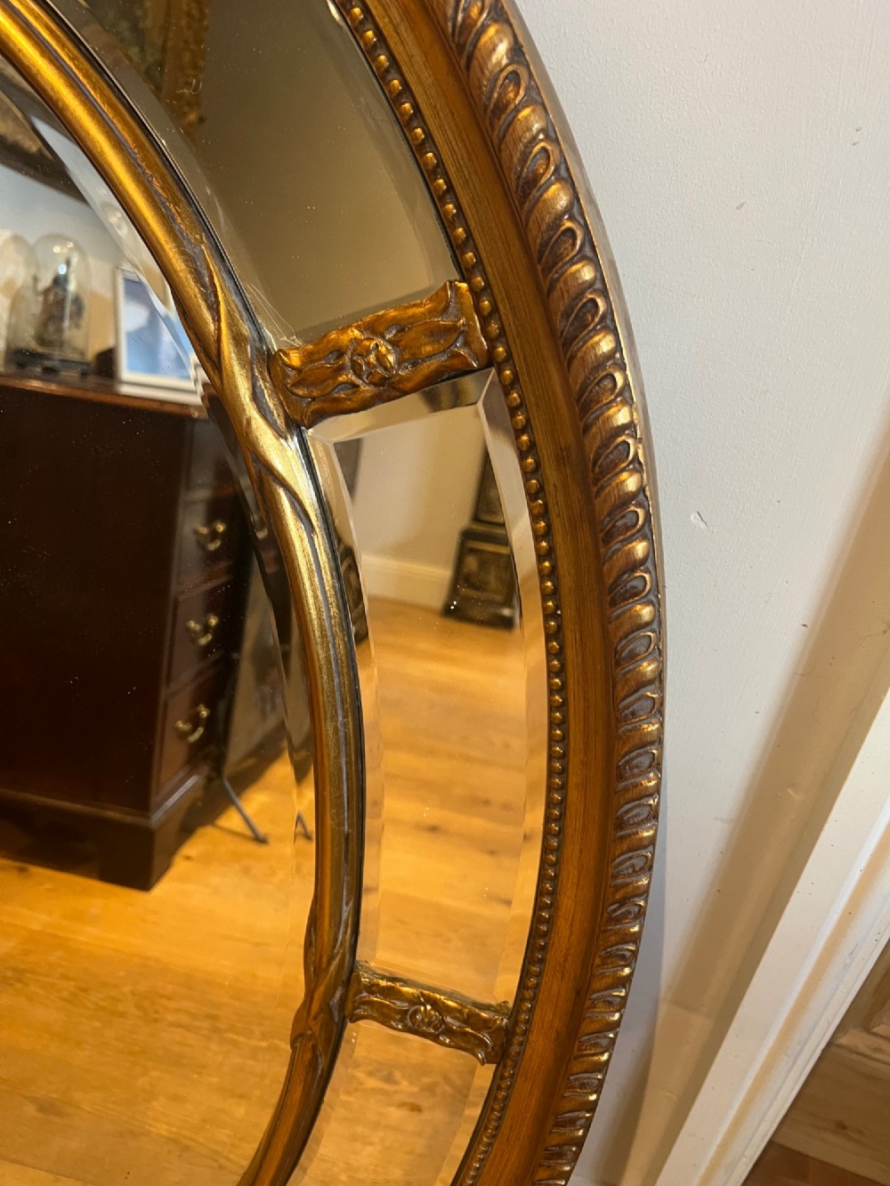 An oval gilded wall mirror featuring a bevelled central mirror surrounded by outer glass margin panels and a gadrooned rim. View III