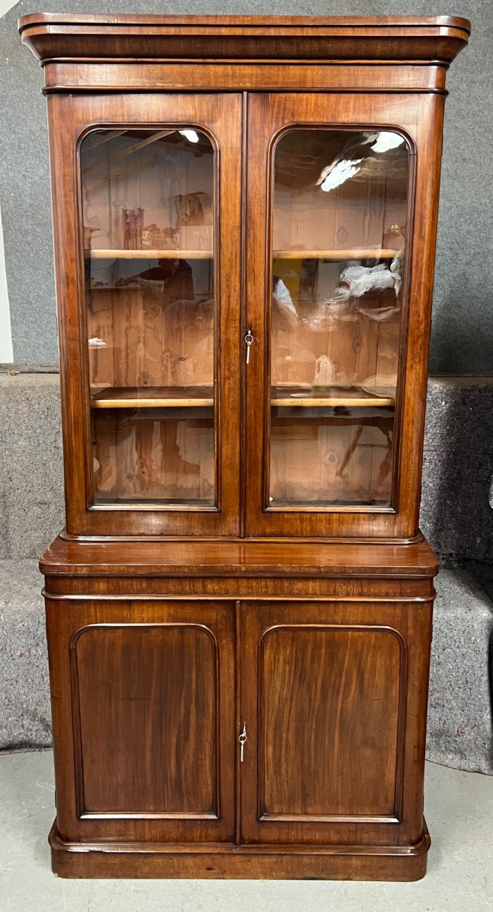 A two-door Victorian mahogany bookcase featuring an upper glazed cabinet with rounded corner panes and a lower enclosed wooden cupboard. View II