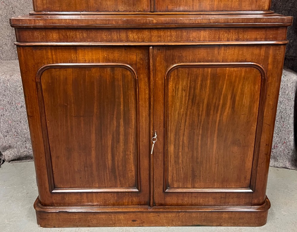 A two-door Victorian mahogany bookcase featuring an upper glazed cabinet with rounded corner panes and a lower enclosed wooden cupboard. View III