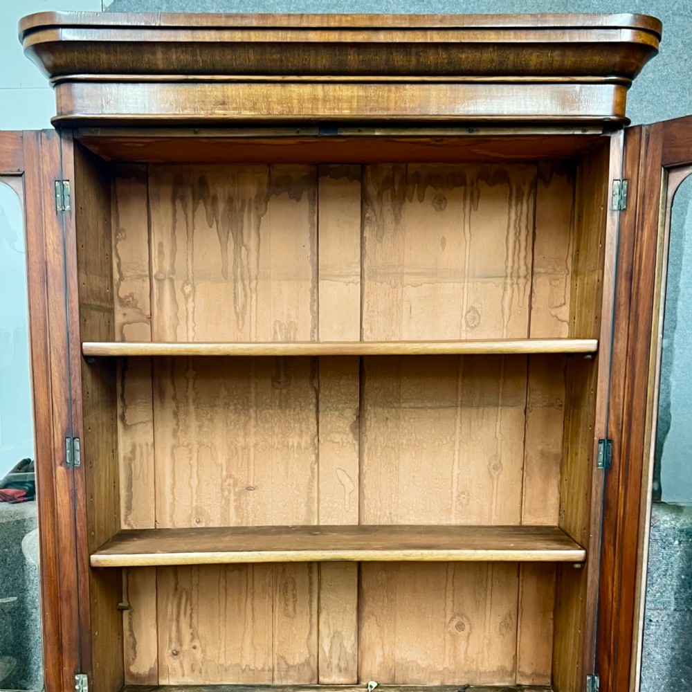 A two-door Victorian mahogany bookcase featuring an upper glazed cabinet with rounded corner panes and a lower enclosed wooden cupboard. View VI