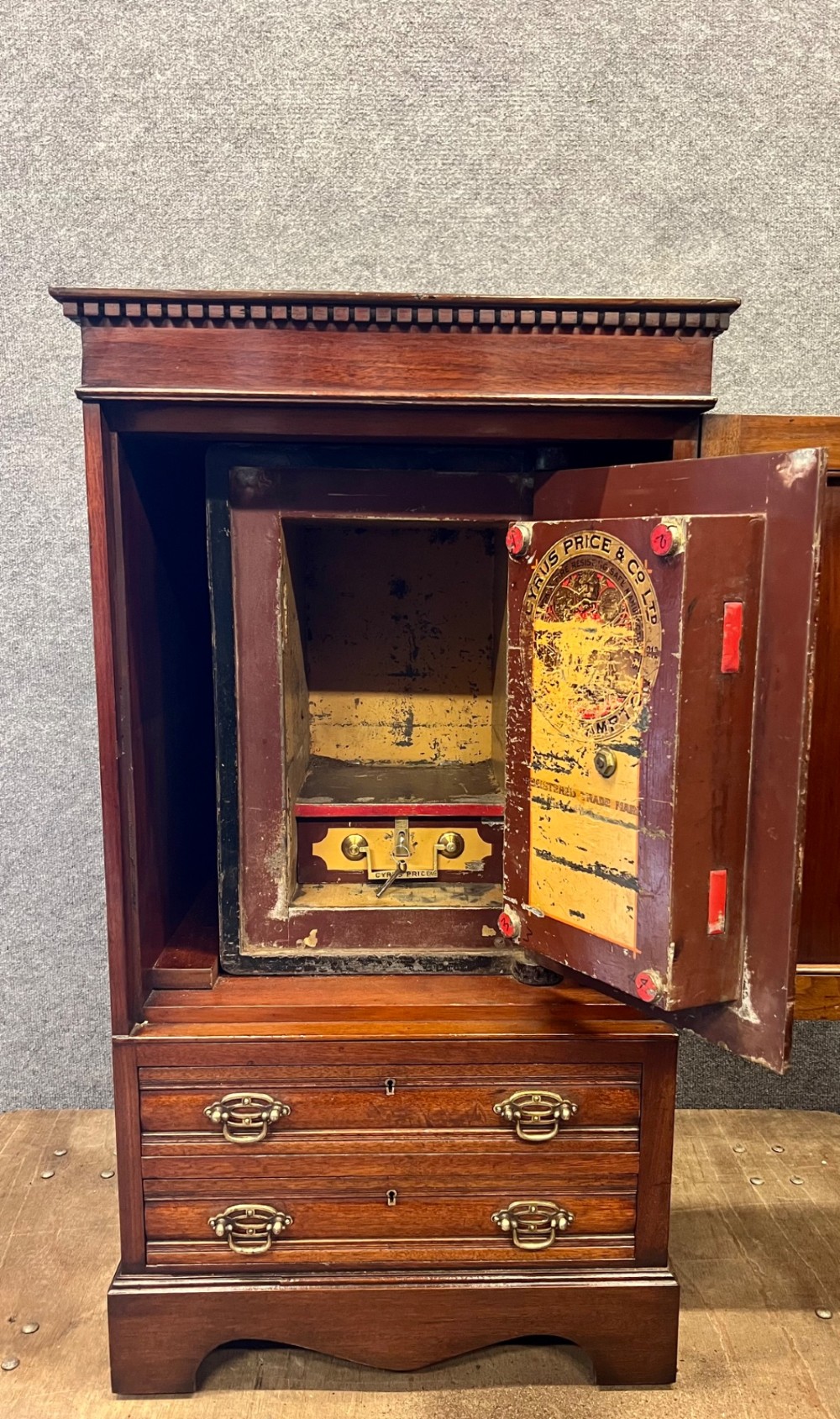 A Victorian mahogany cabinet with an open door revealing an internal Cyrus Price and Company iron safe above two lower drawers. View II