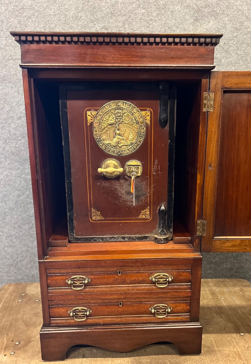 A Victorian mahogany cabinet with an open door revealing an internal Cyrus Price and Company iron safe above two lower drawers.