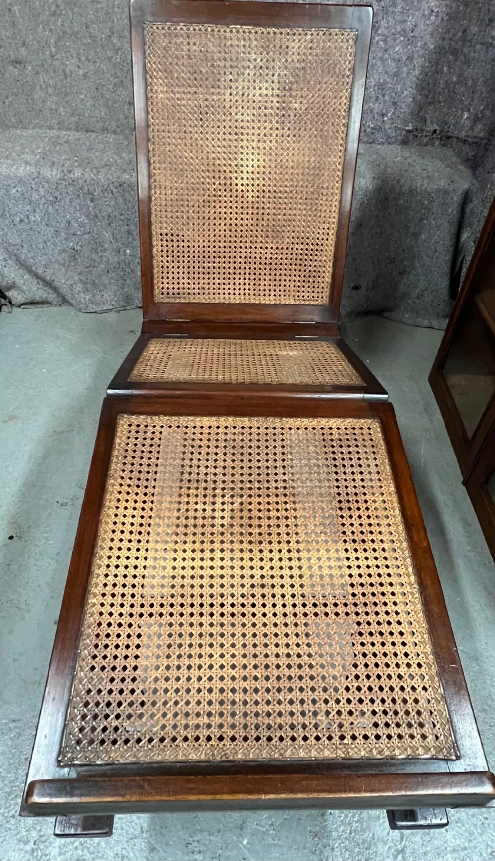 An antique mahogany campaign bed featuring three hinged folding sections with woven cane panelling and a dark timber frame.