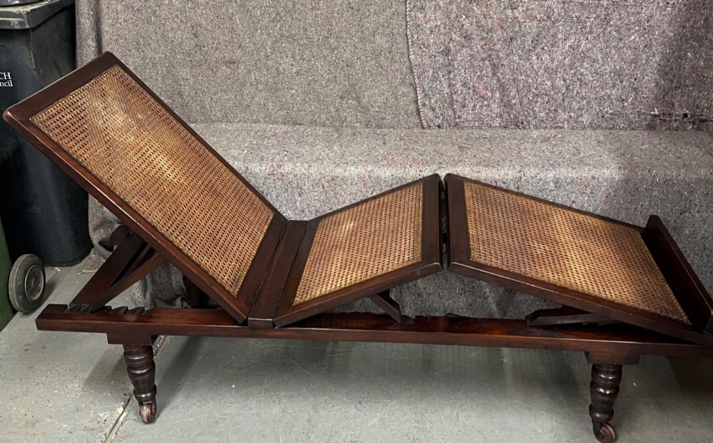 An antique mahogany campaign bed featuring three hinged folding sections with woven cane panelling and a dark timber frame. View II