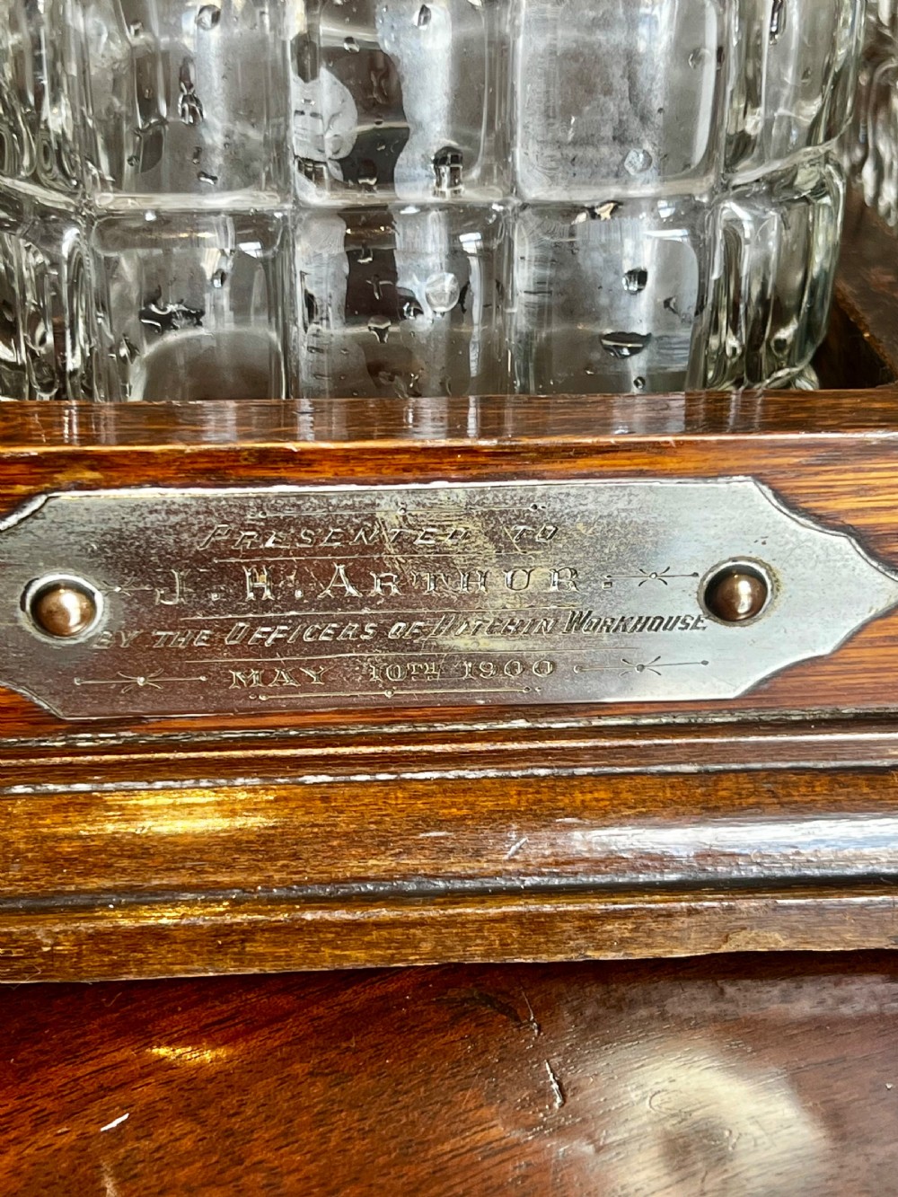 An antique Edwardian oak tantalus housing three cut-glass decanters with matching silver labels, fitted with a brass handle and locking mechanism. View V
