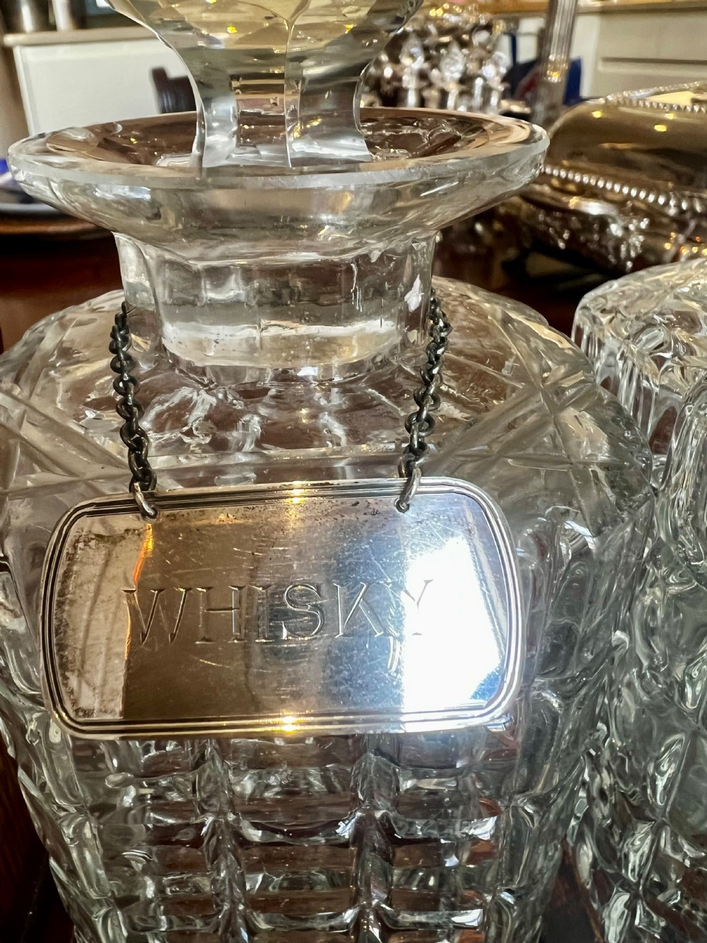 An antique Edwardian oak tantalus housing three cut-glass decanters with matching silver labels, fitted with a brass handle and locking mechanism. View VI