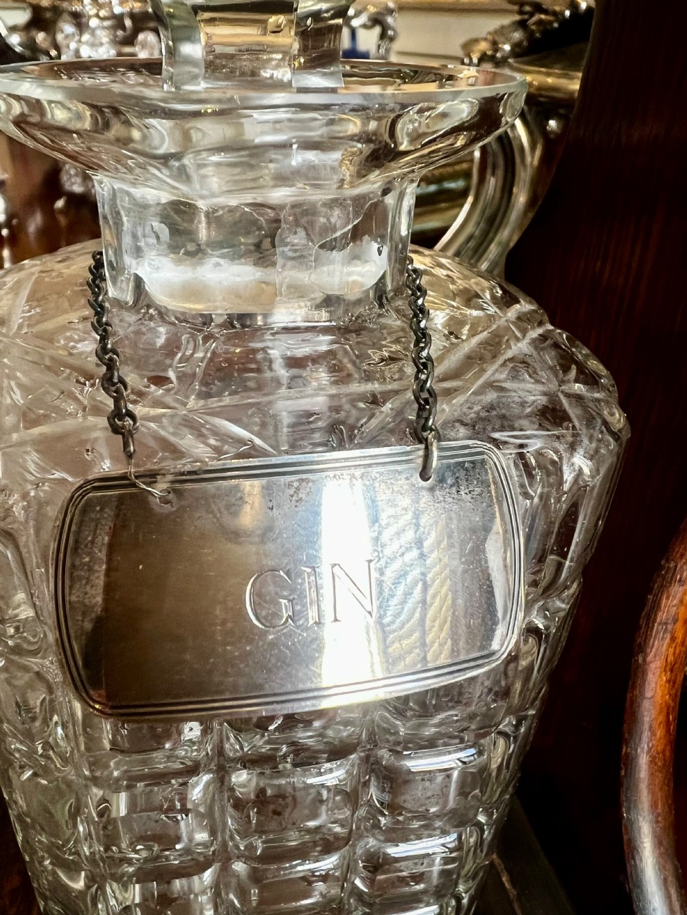 An antique Edwardian oak tantalus housing three cut-glass decanters with matching silver labels, fitted with a brass handle and locking mechanism. View VII