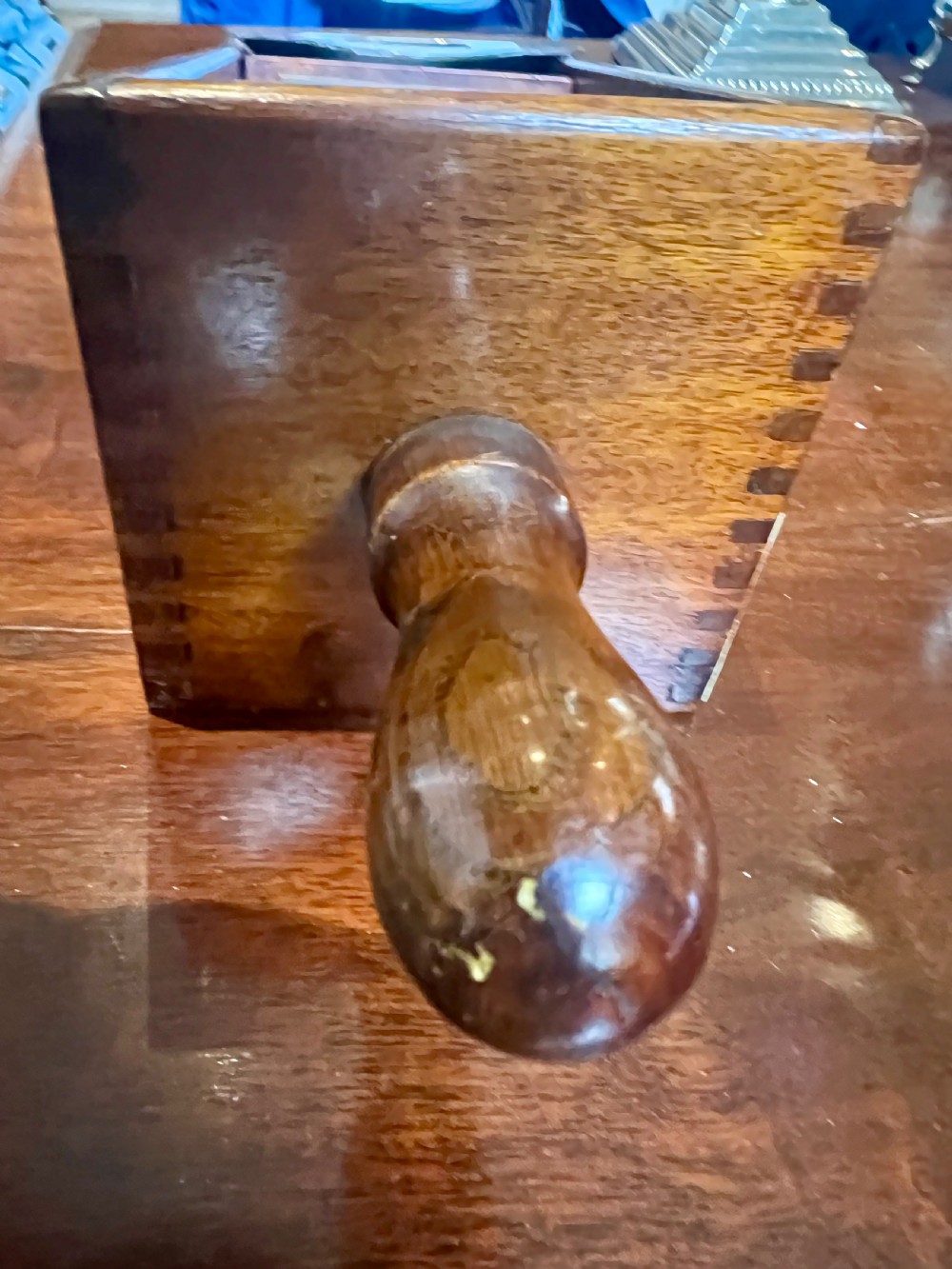 A vintage mahogany card shoe featuring a brass weighted dispensing mechanism and exposed grain. View V