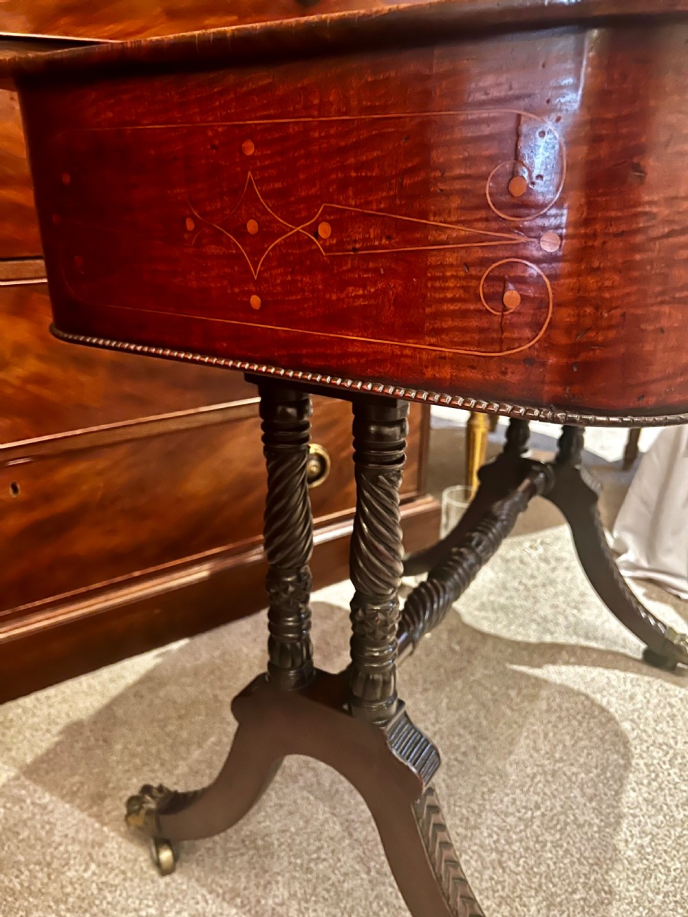 An antique dark wood Regency reading table featuring an adjustable sloped top, small drawers with brass key escutcheons, and carved intersecting legs with castors. View III