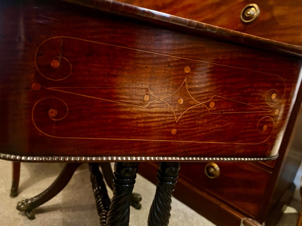 An antique dark wood Regency reading table featuring an adjustable sloped top, small drawers with brass key escutcheons, and carved intersecting legs with castors. View VIII