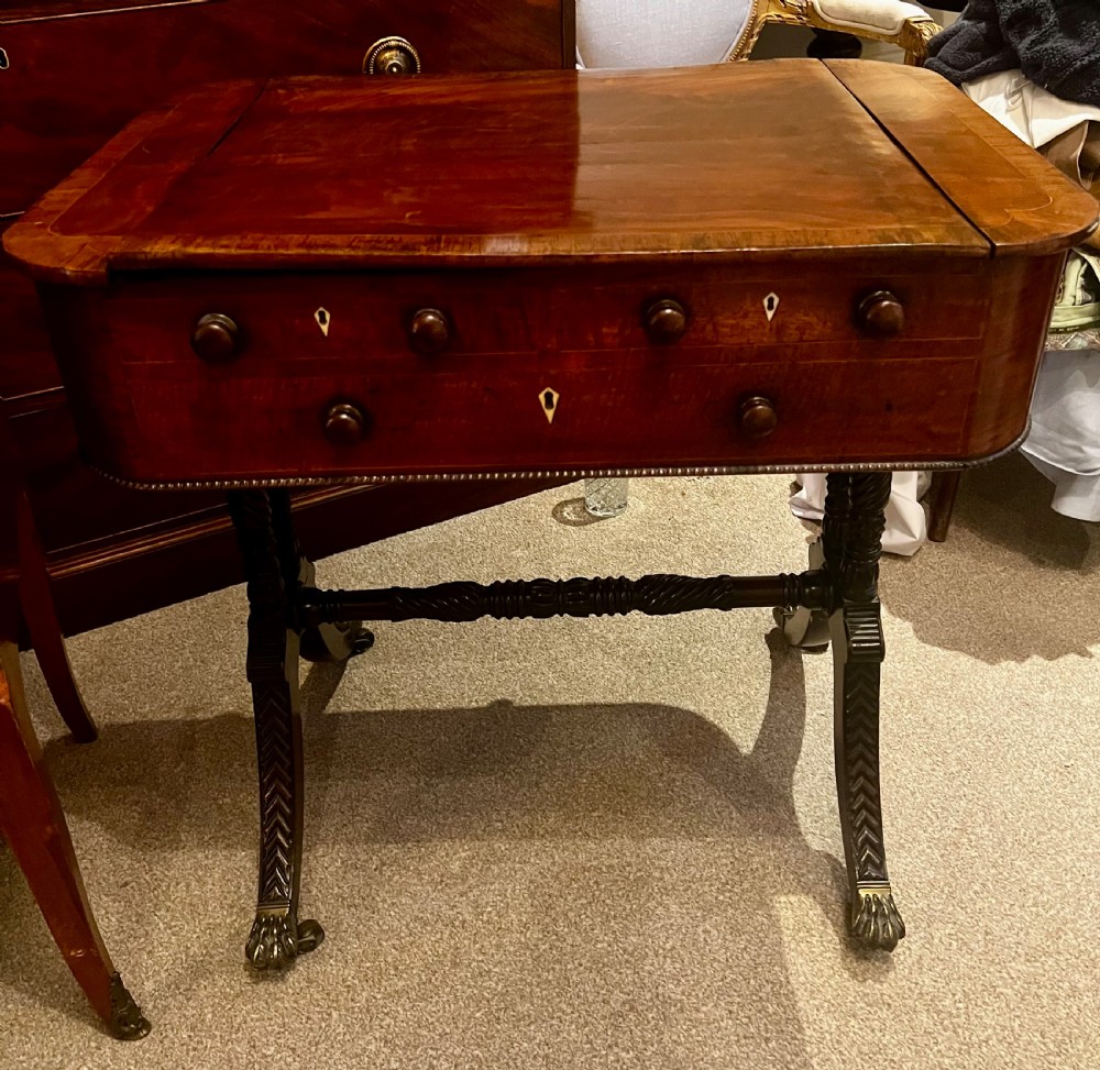 An antique dark wood Regency reading table featuring an adjustable sloped top, small drawers with brass key escutcheons, and carved intersecting legs with castors. View IX