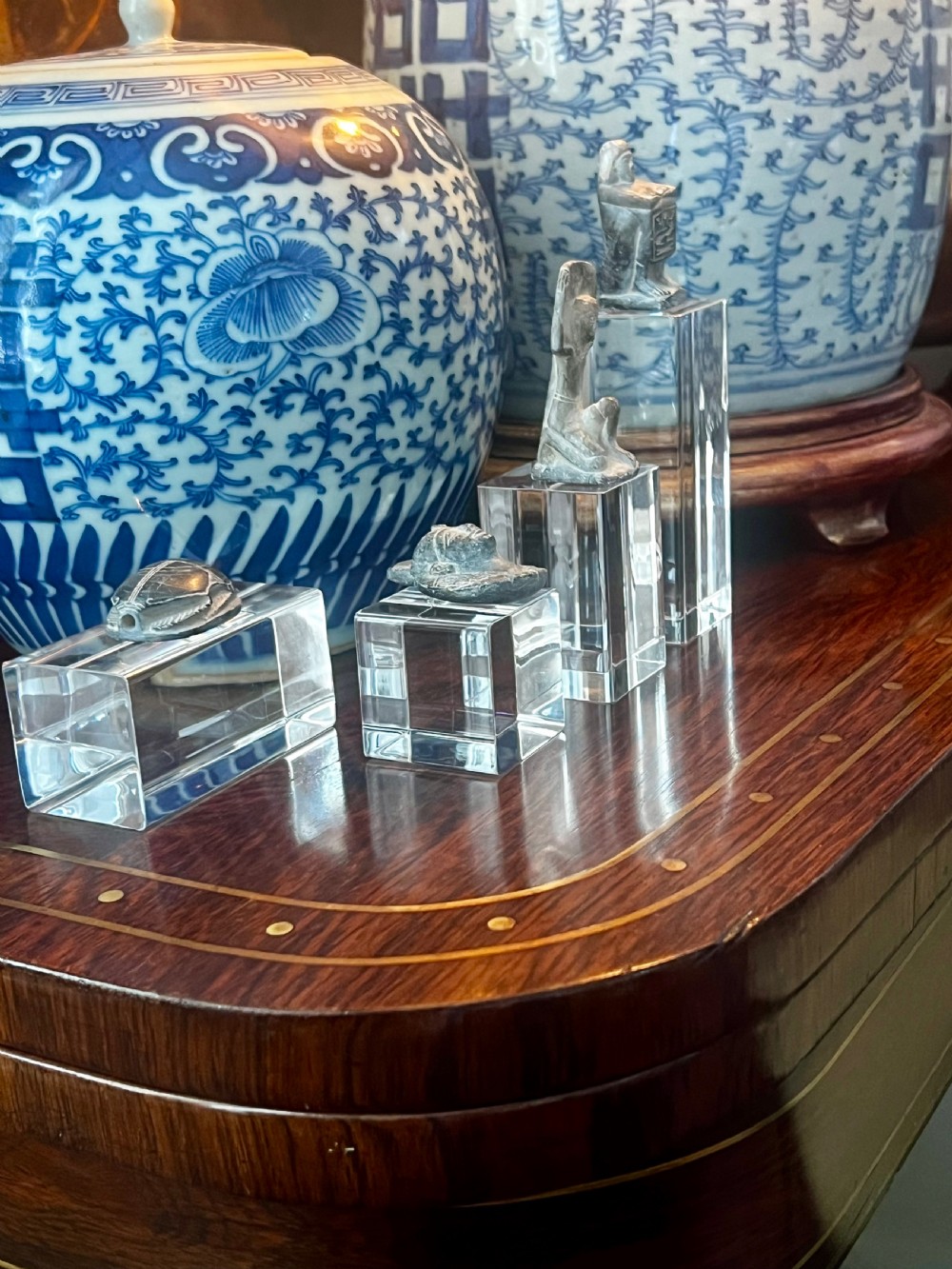 Four carved grey stone Egyptian scarabs and deity figurines displayed individually on clear acrylic block stands.