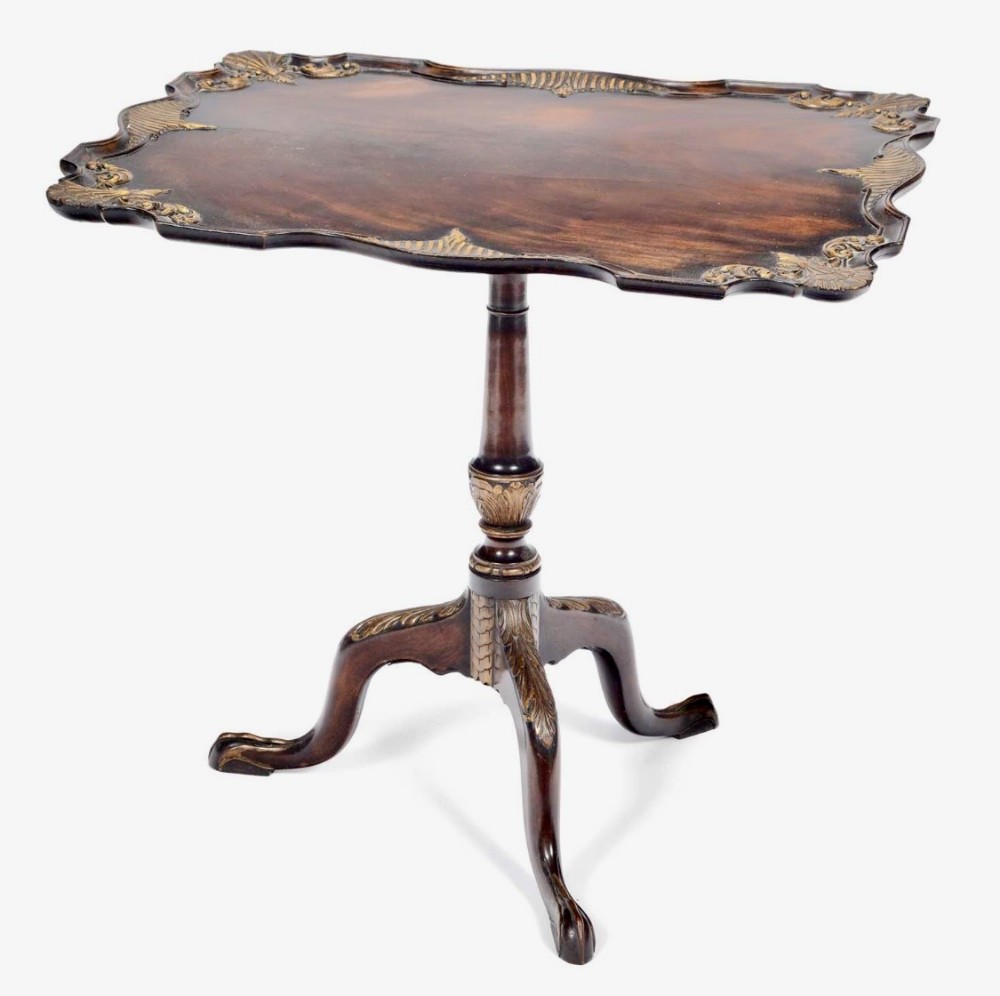 A nineteenth-century mahogany tilt-top tripod table featuring parcel gilt decorative accents, a shaped rim, turned pedestal, and carved cabriole legs.