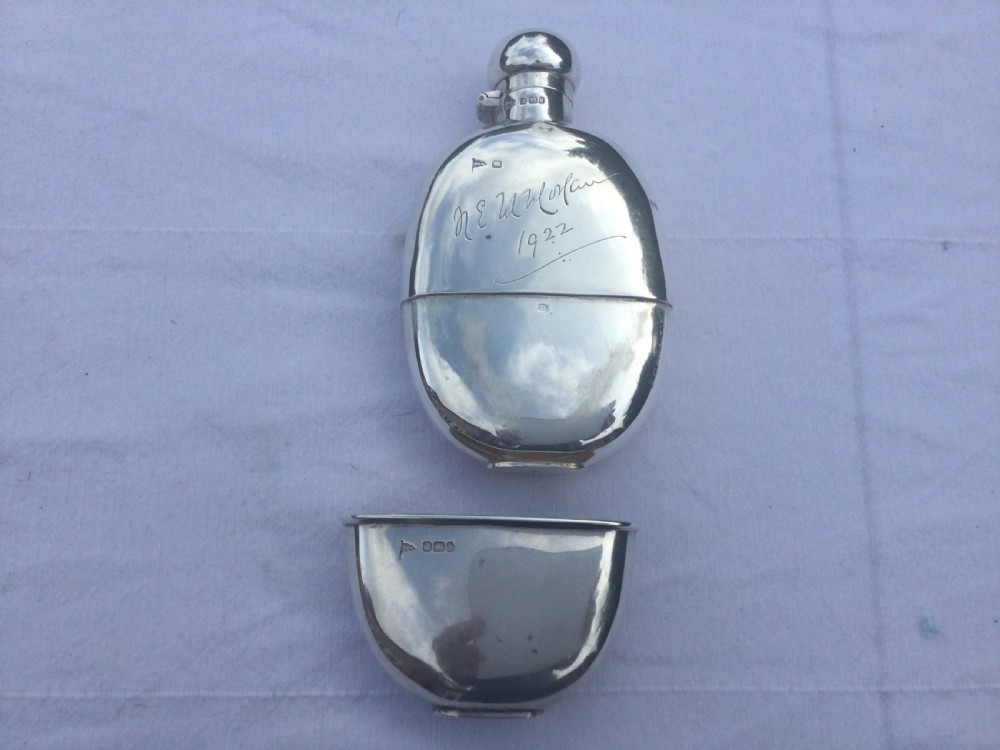 A curved silver hip flask featuring an engraved signature dated 1922, hallmarked collar, and a hinged domed cap. View VI