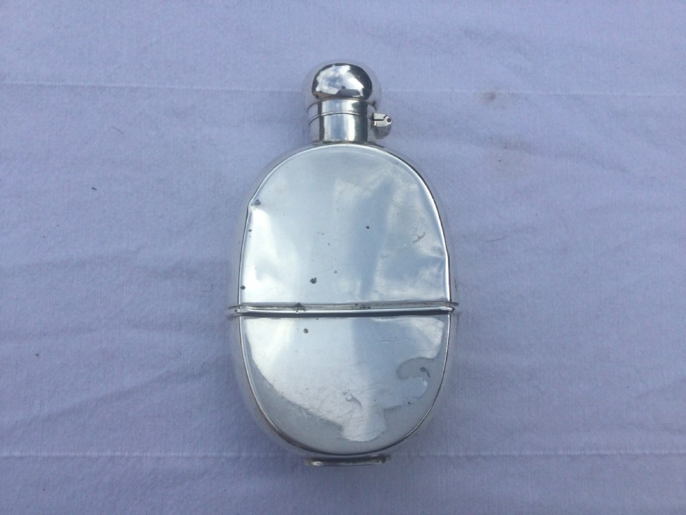 A curved silver hip flask featuring an engraved signature dated 1922, hallmarked collar, and a hinged domed cap. View VII