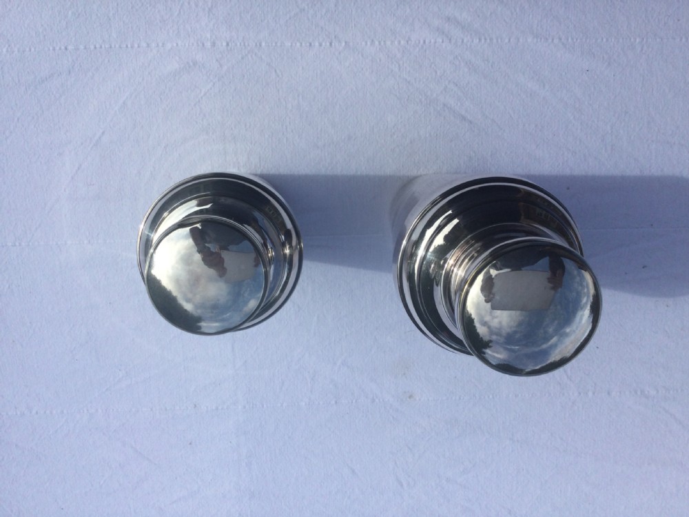 A pair of polished silver-plated Art Deco cocktail shakers featuring stepped caps and ribbed band details on their tapered bodies. View II