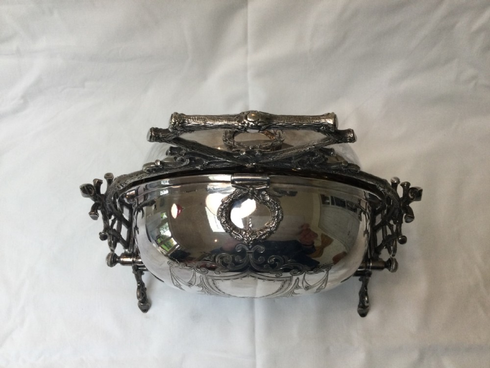 A Victorian silver-plated revolving biscuit barrel featuring engraved foliage patterns, mounted within an ornate cast twig-form metal stand. View III