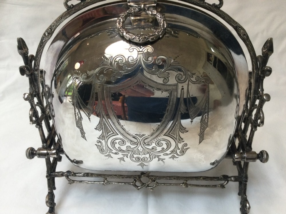 A Victorian silver-plated revolving biscuit barrel featuring engraved foliage patterns, mounted within an ornate cast twig-form metal stand. View IV