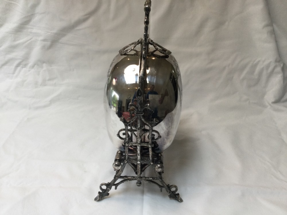A Victorian silver-plated revolving biscuit barrel featuring engraved foliage patterns, mounted within an ornate cast twig-form metal stand. View V