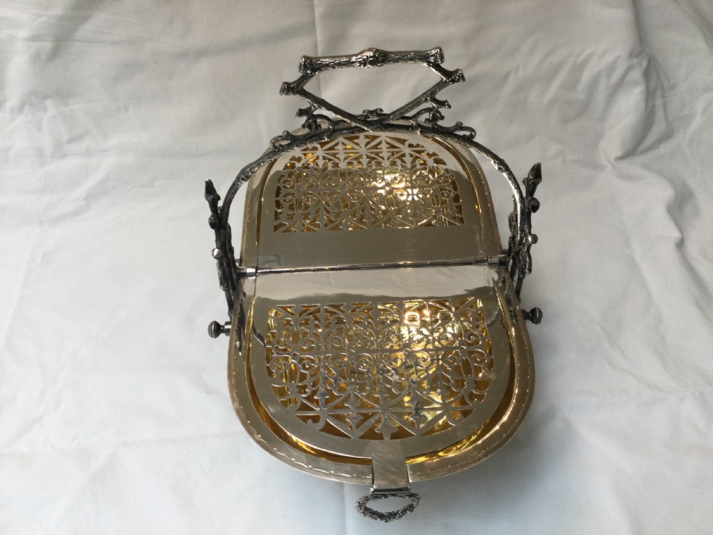 A Victorian silver-plated revolving biscuit barrel featuring engraved foliage patterns, mounted within an ornate cast twig-form metal stand. View VII