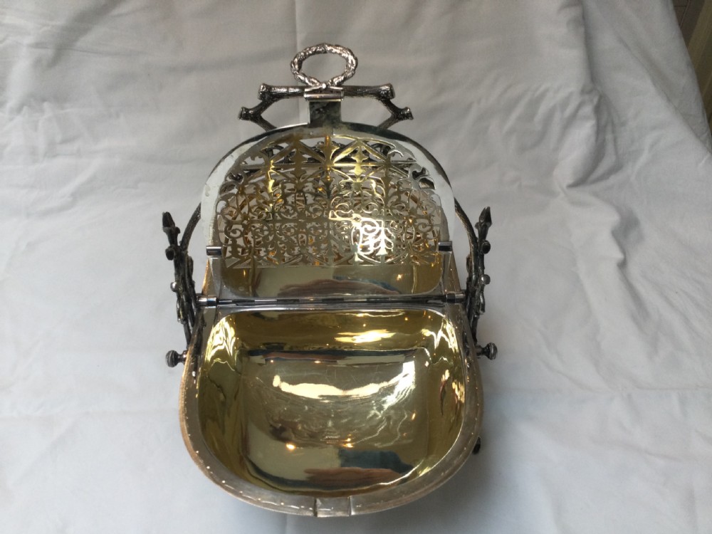 A Victorian silver-plated revolving biscuit barrel featuring engraved foliage patterns, mounted within an ornate cast twig-form metal stand. View VIII