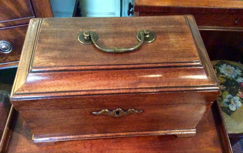 A Georgian mahogany tea caddy featuring a moulded stepped lid, a top brass handle, a brass keyhole escutcheon, and bracket feet. View VI