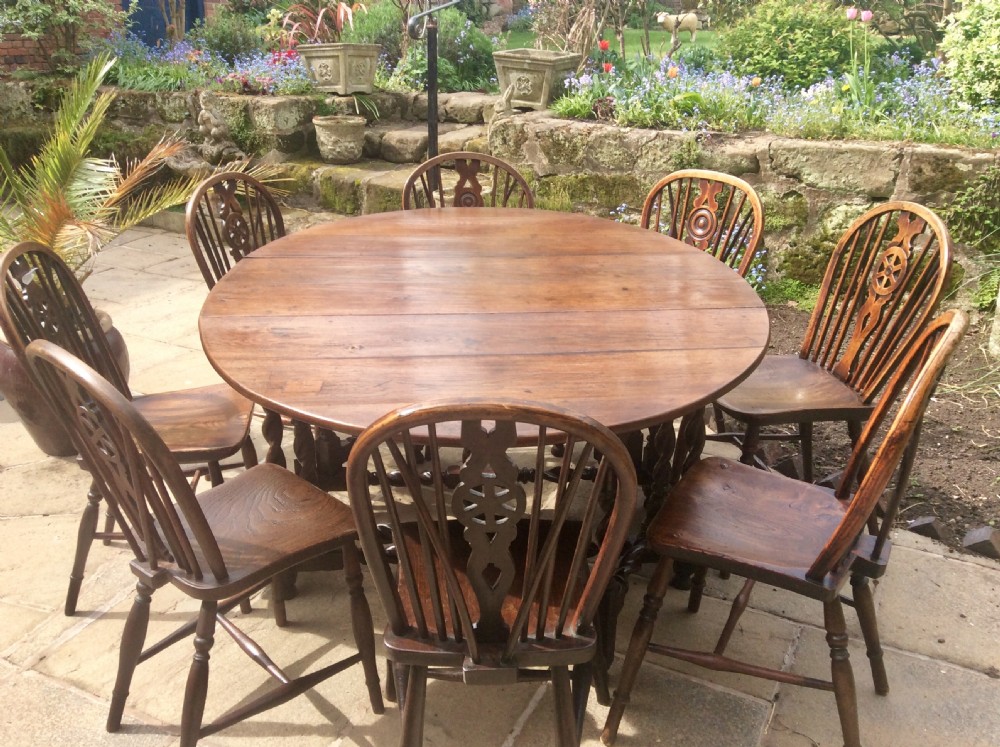 An antique dark oak oval gateleg table featuring barley twist turned legs, stretchers, and folding drop leaves. View VI