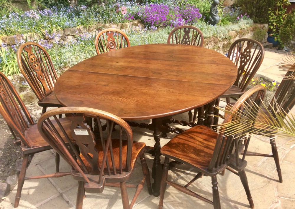 An antique dark oak oval gateleg table featuring barley twist turned legs, stretchers, and folding drop leaves. View VII