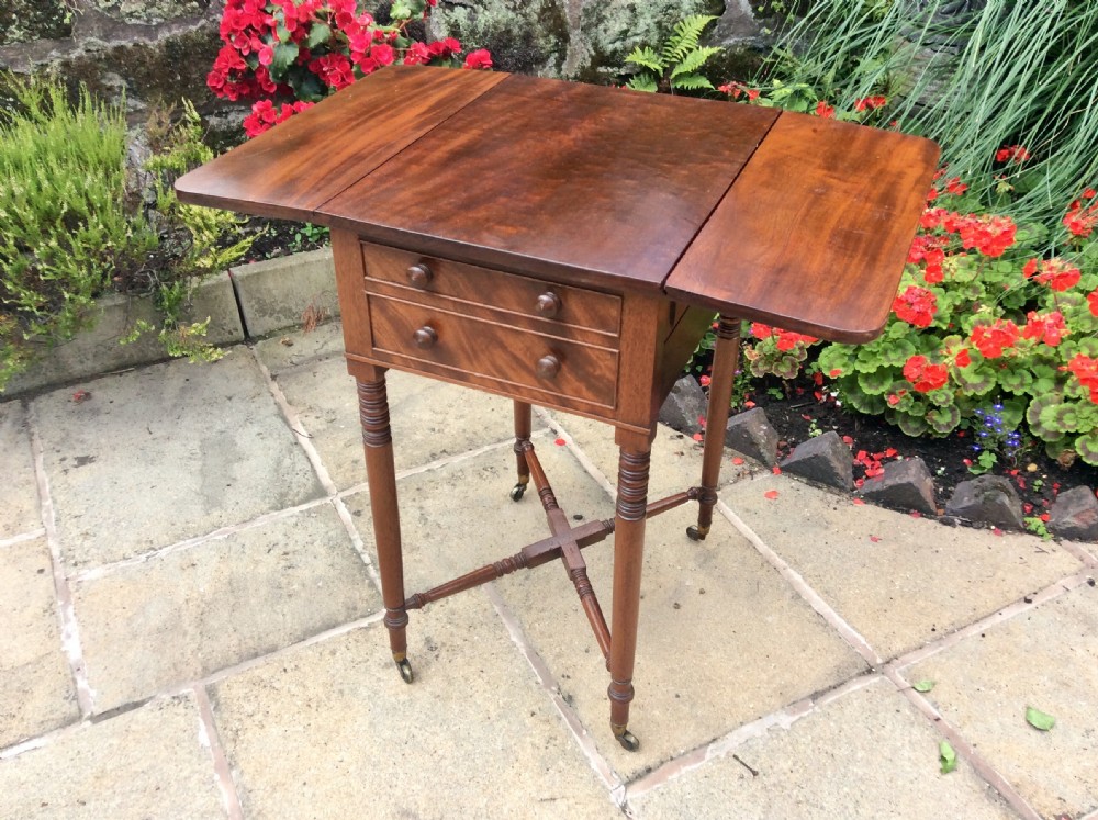 A Regency mahogany Pembroke table featuring two drawers, drop-leaf sides, turned reeded legs, a cross-stretcher, and brass castors. View VI